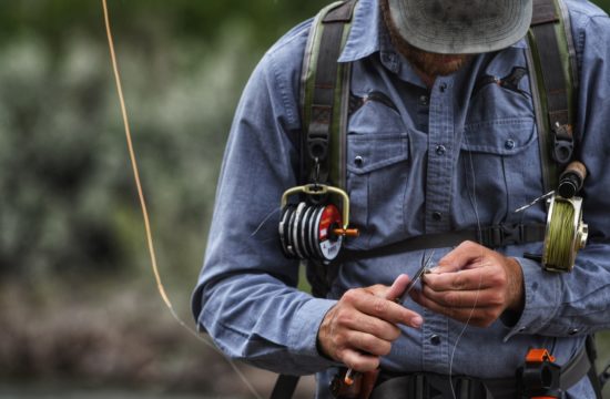 A fly fishing guide uses a pocket knife to cut fishing line near CM Ranch in Dubois, WY | Wyoming dude ranch vacations